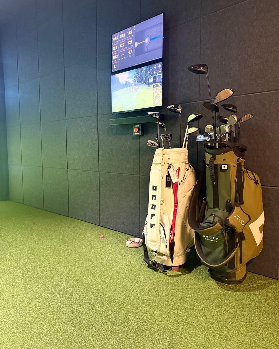 Golfbags und Schläger neben dem TrackMan Bildschirm