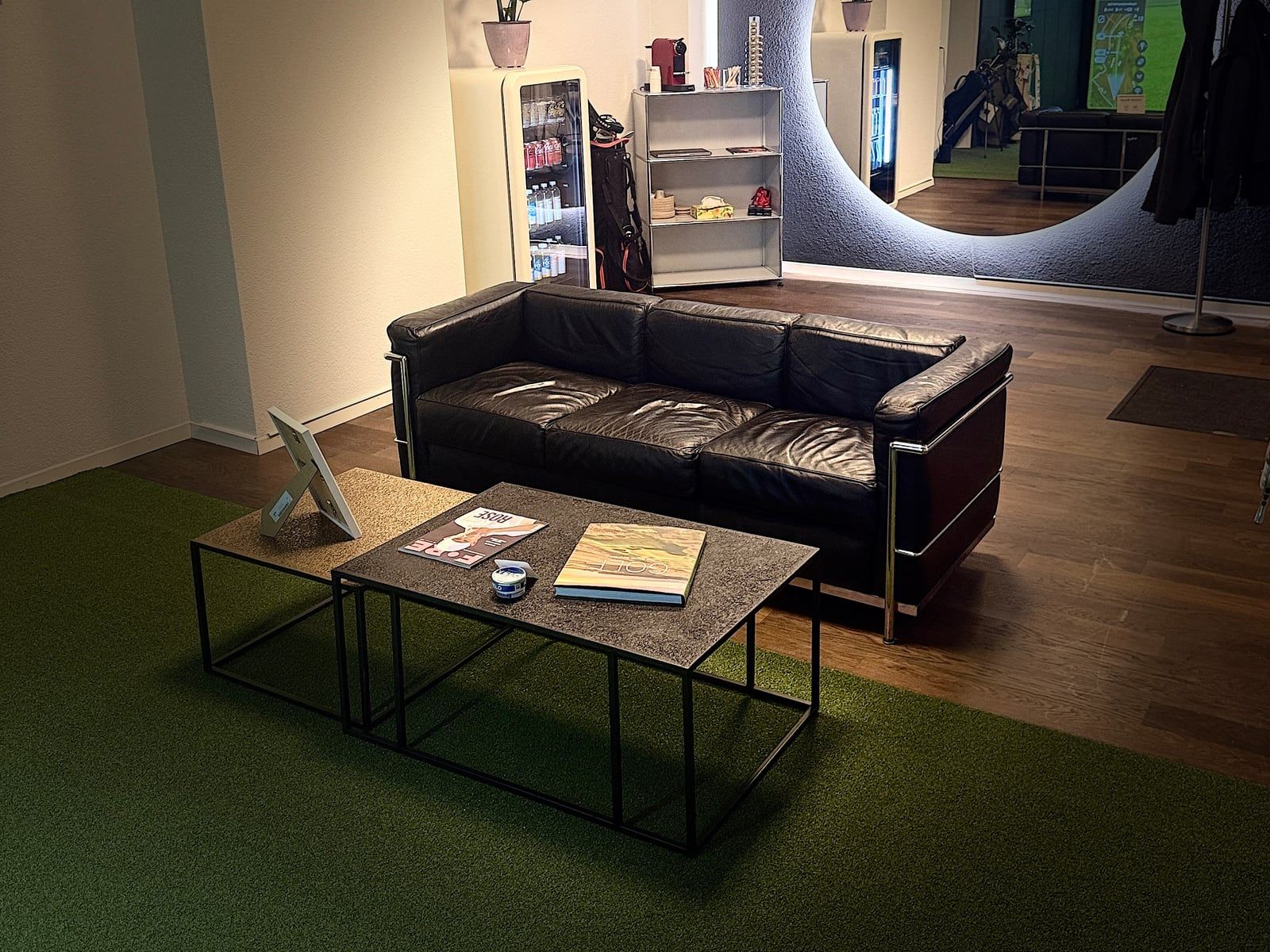 Lounge mit Ledersofa, Couchtisch und beleuchtetem Spiegel im Golf Room